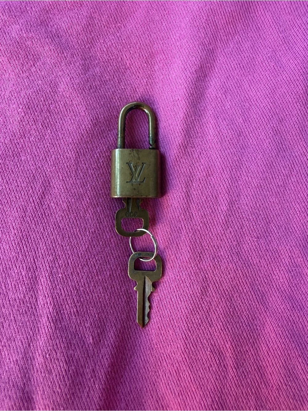 Louis Vuitton Brass Padlock and Key on Pink Background